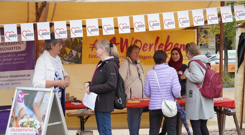 AWO erleben Stand mit gelben Banner. Menschen beraten interessierte Ehrenamtssuchende.